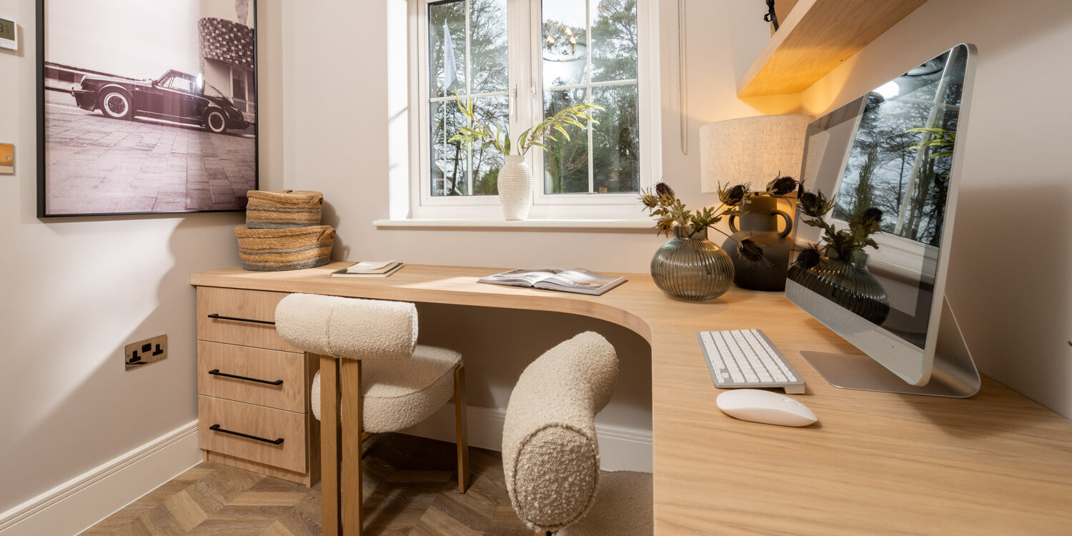 office with wooden desk and drawers and cream soft chairs with window and blind to the rear