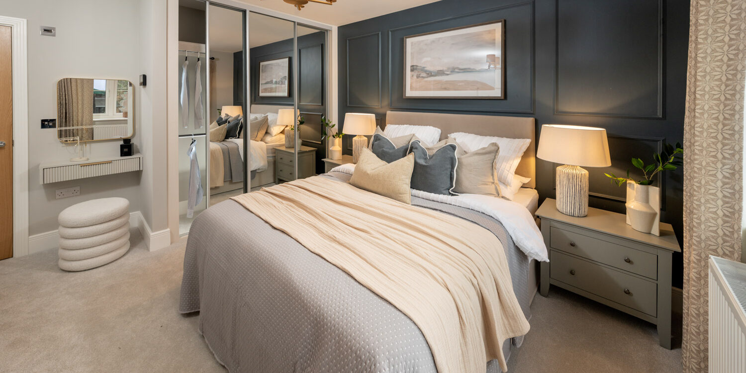 blue and cream coloured bedroom with made up bed and walk in wardrobe to the rear