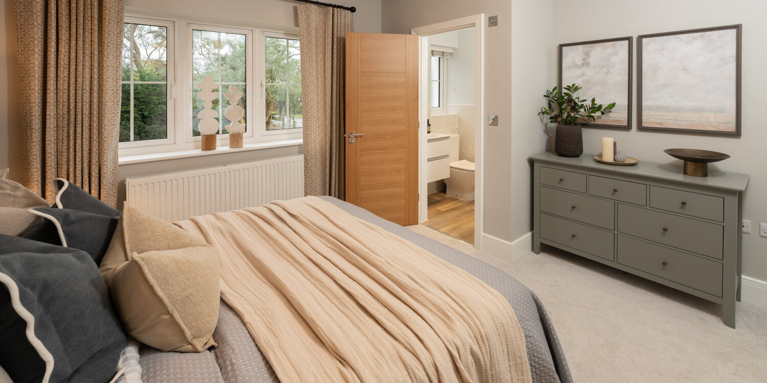 blue and cream coloured bedroom with window to the left. made up bed and door opening to en-suite shower to the rear